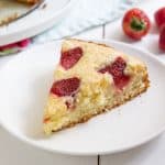 a piece of strawberry cake with a strawberry in the background