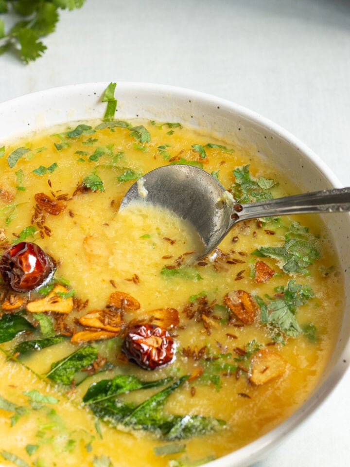 a dish of masoor ki daal with a spoon in it