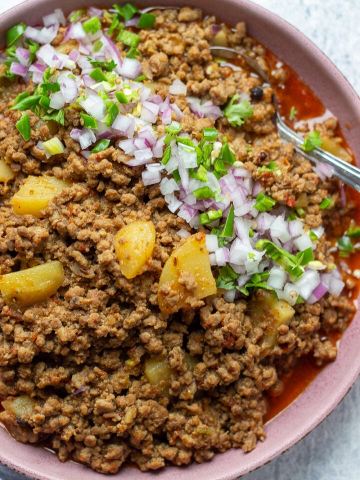 Aaloo Keema or Keema Aloo top down view garnished with onions and cilantro