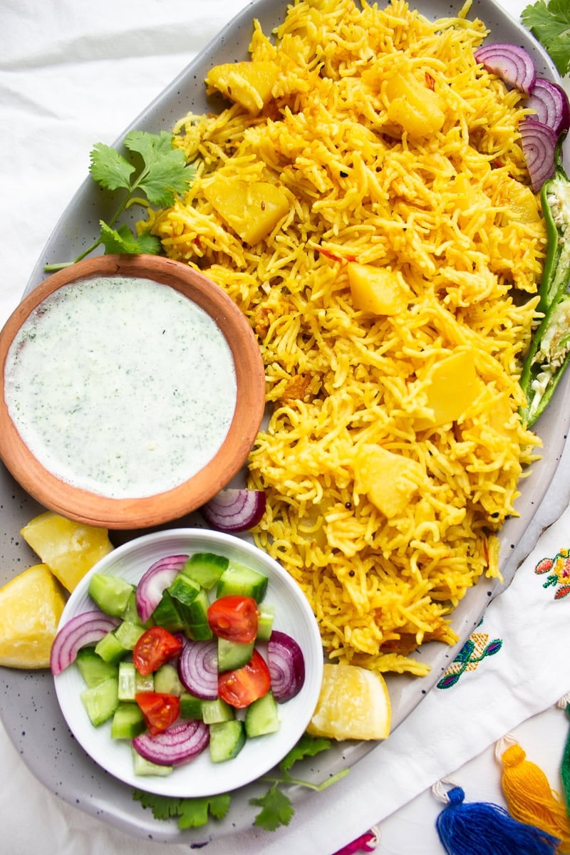 top down view of a tehri dish with raita and a chopped salad