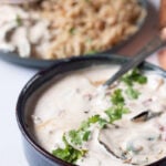 ¾ view of a dish of sabzi raita with a plate of rice in the background