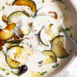 top down view of dahi baingan with sliced cooked eggplant peeking through