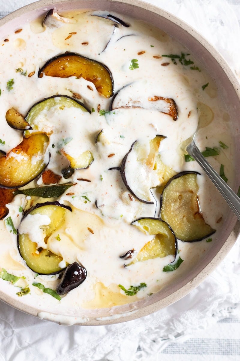 top down view of dahi baingan or baingan ka raita in a pink dish