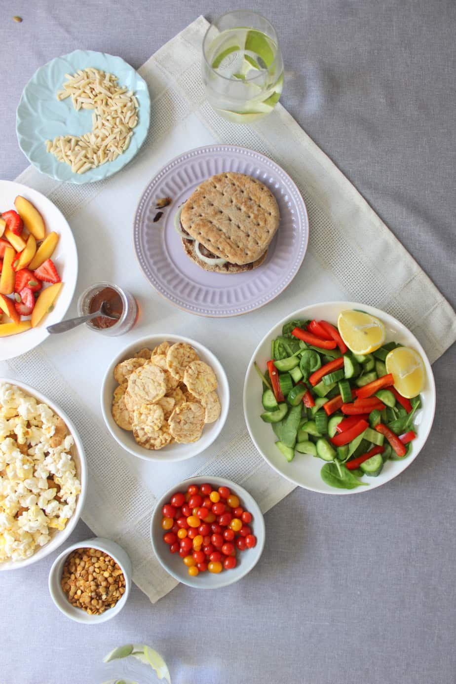 A variety of fresh foods on a light tablecloth, including a sandwich, salad with lemon, and more—just the kind of balanced meal a Loblaws in-store registered dietitian might recommend.