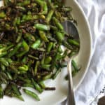 a white plate with lightly charred green beans