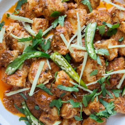 a close up of a dish of Karhai Chicken with green chilies,ciilantro and ginge