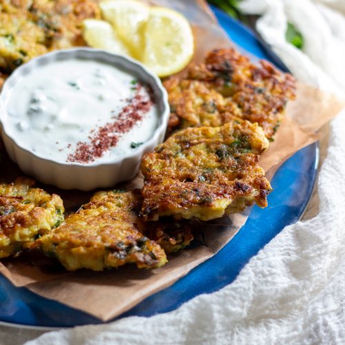 ¾ view of a plate of cauliflower fritters with the mint yogurt in the center