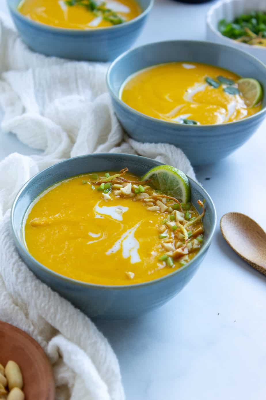 One full and two partial bowls of carrot soup