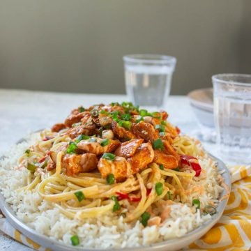 a dish of singaporean rice with two glasses of water in the background