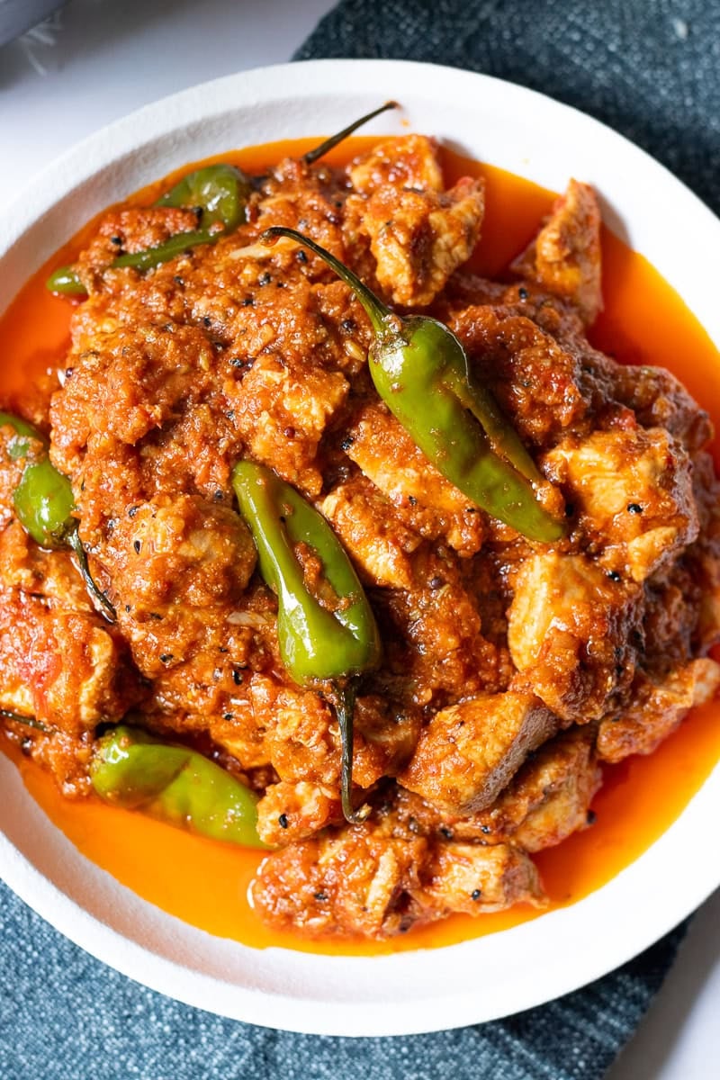 top down view of chicken achari in a white plate