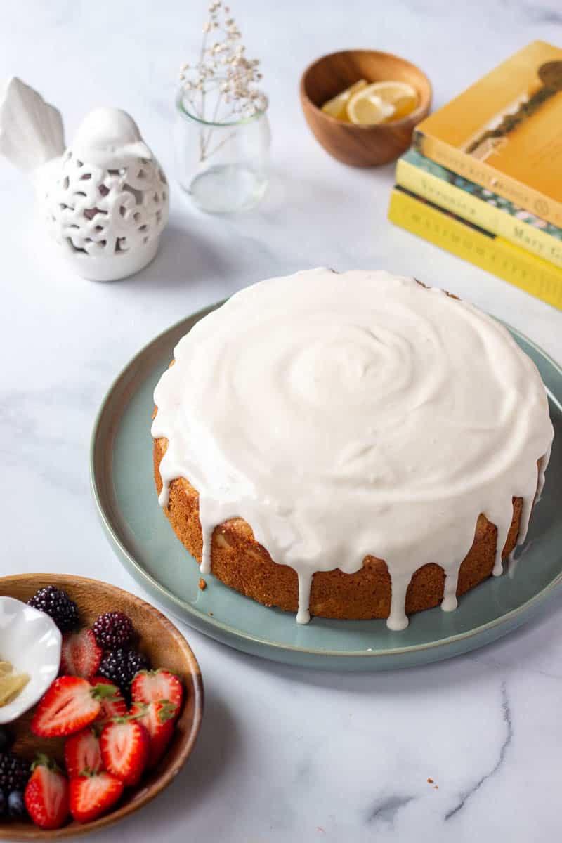 A lemon cake with cream cheese glaze and some yellow and white decorative elements in the back ground