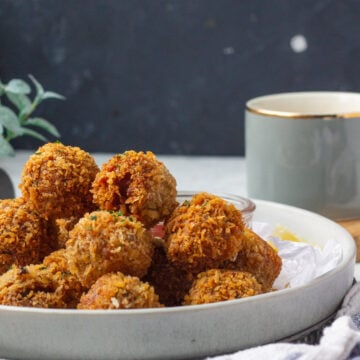 fried chicken balls mounded ina plate, a cup in the background