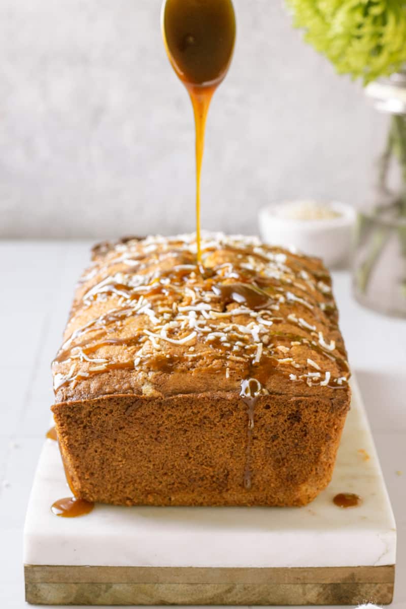 Caramel sauce being drizzled on a coconut cake