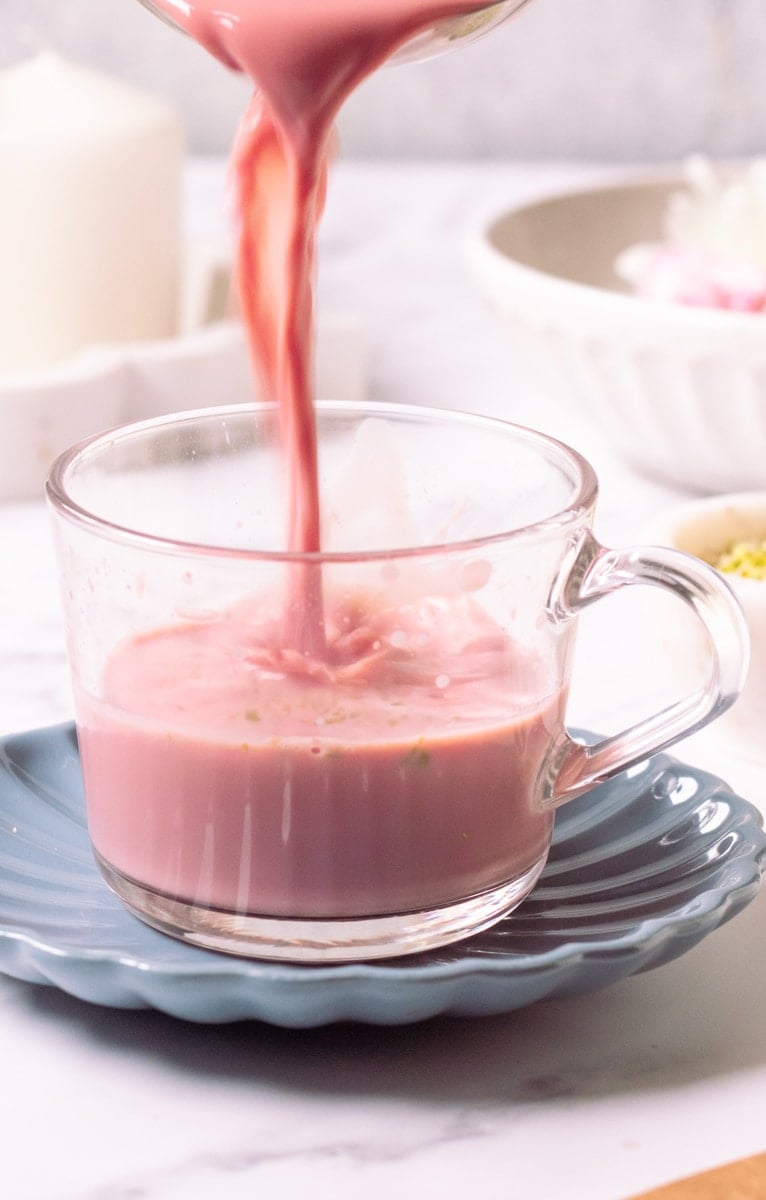 Kashmiri tea being laded into a cup on a blue saucer