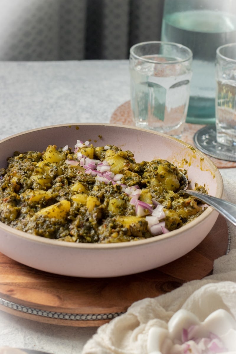 pink dish with pakistani style potato and spinach curry