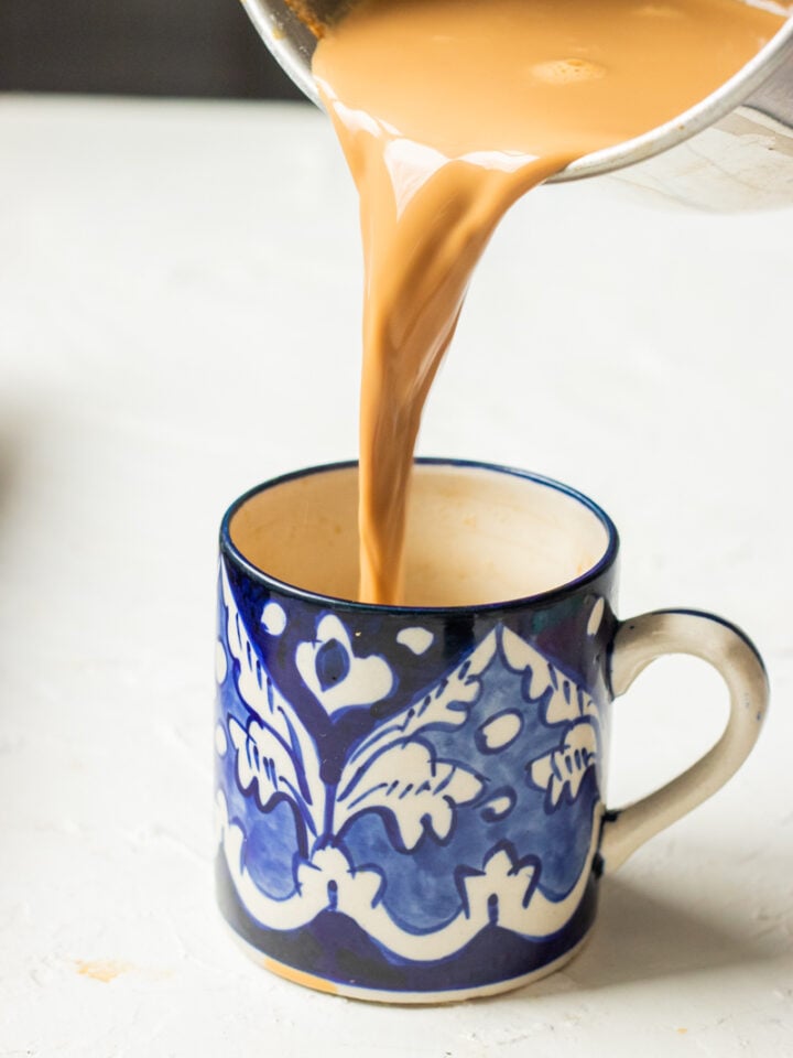 doodh patti being poured into a cup