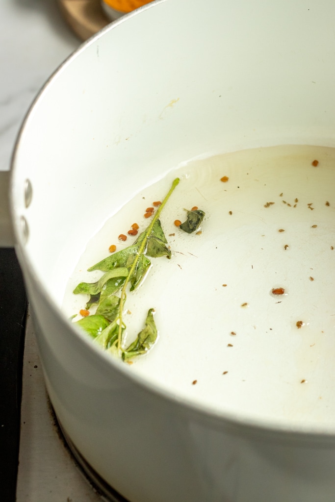 frying spices and curry leaves in oil