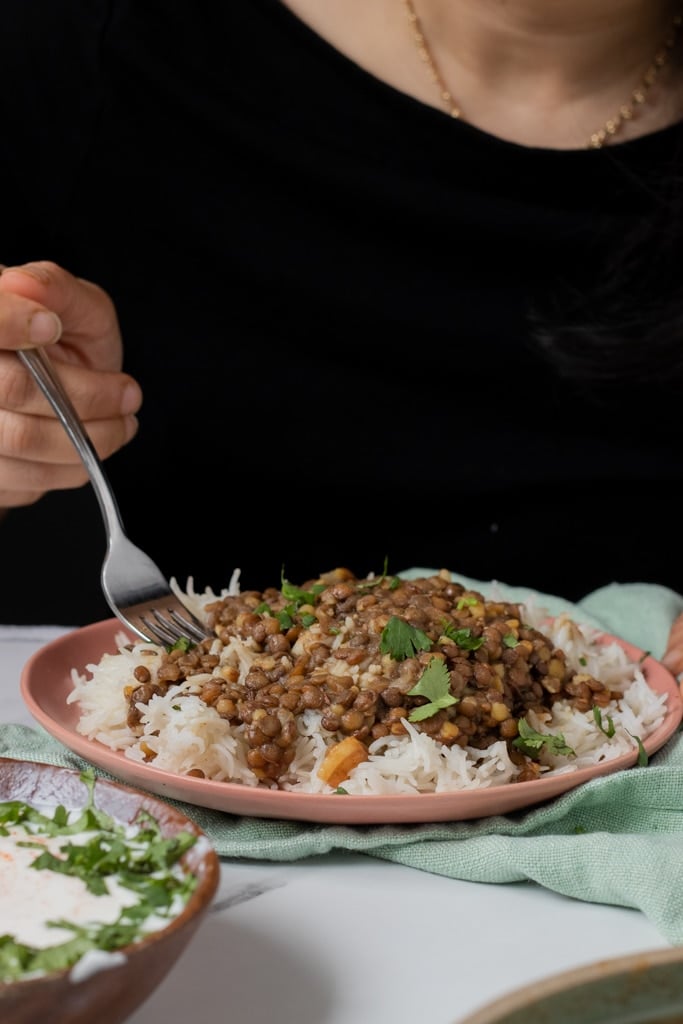 Kaali Daal chawal on a plate, person in the background eating