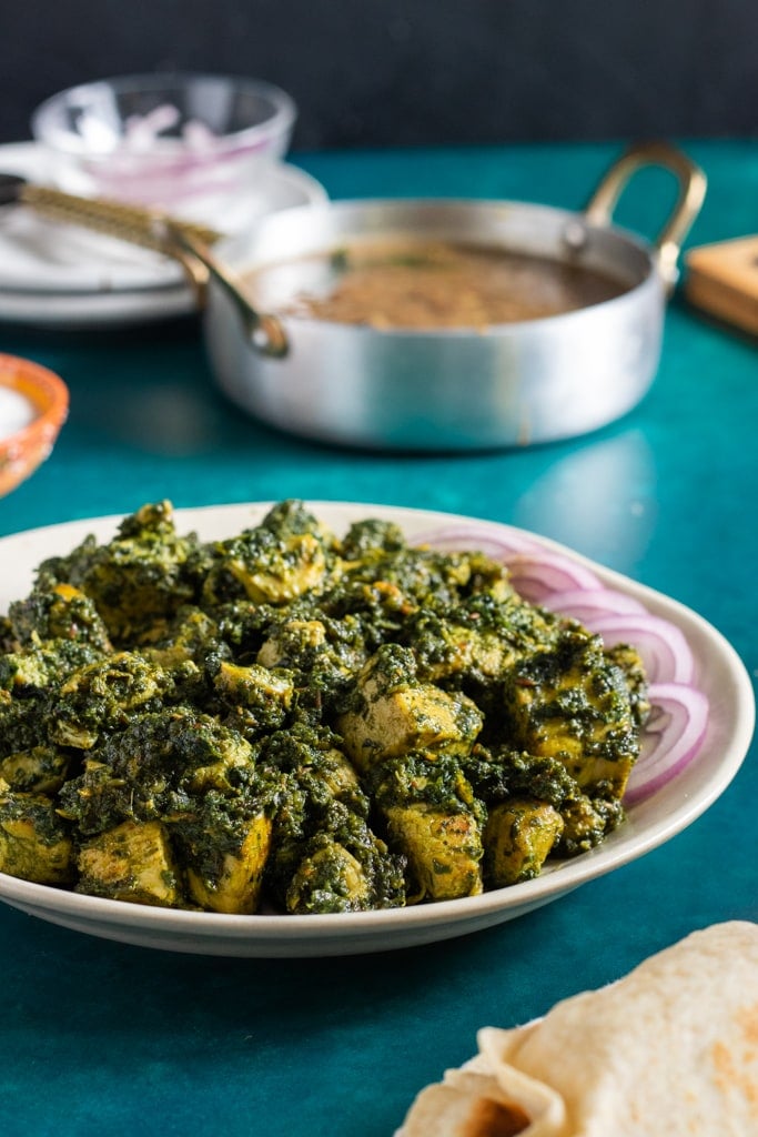 Murgh Palak on a plate with a pot in the background