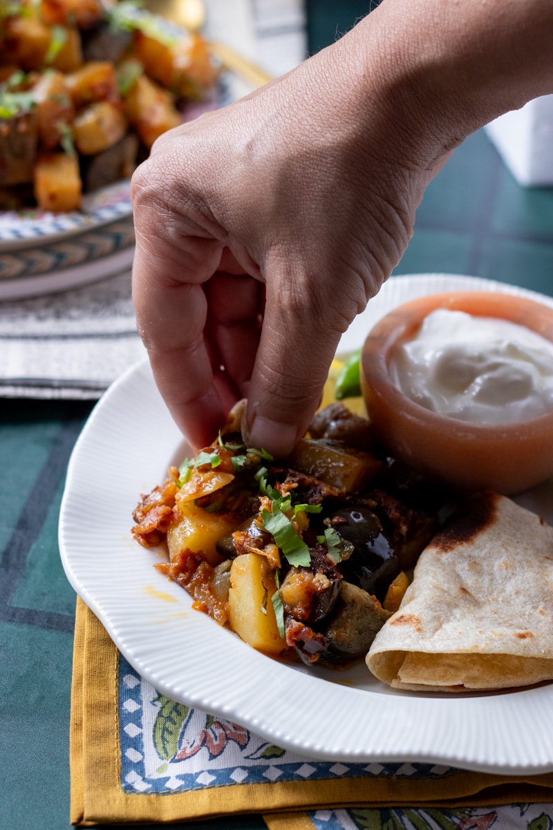 a hand making a niwala of aloo baingan with chapati