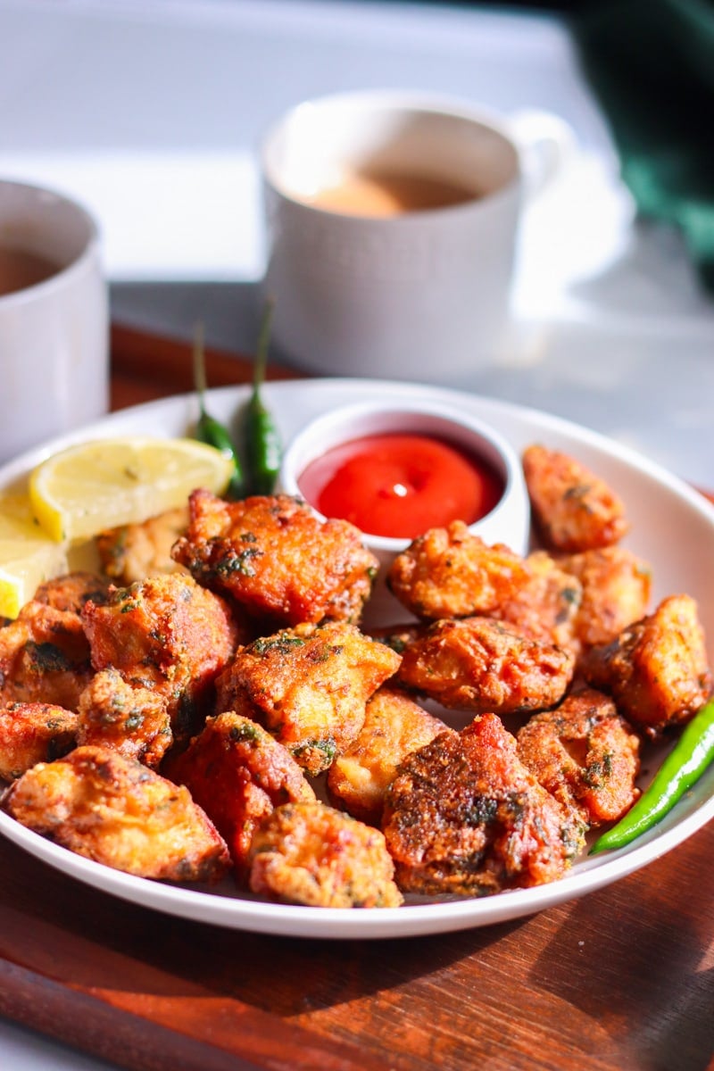 a plate of crunchu chicken pakoray, chai cups in the background