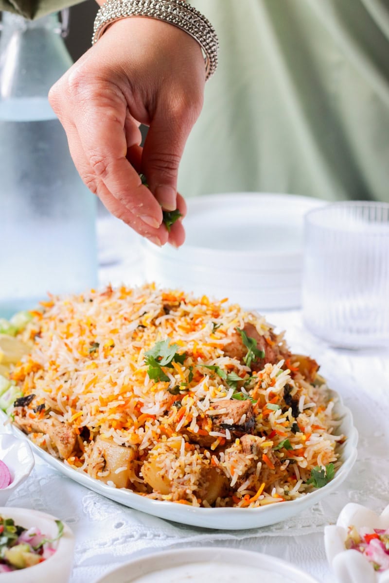 hand garnishing dhania on biryani plate