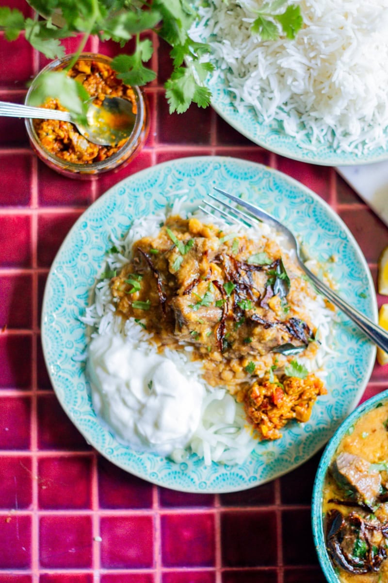 top down view of a plate of dal gosht and plain yoghurt with rice and achar