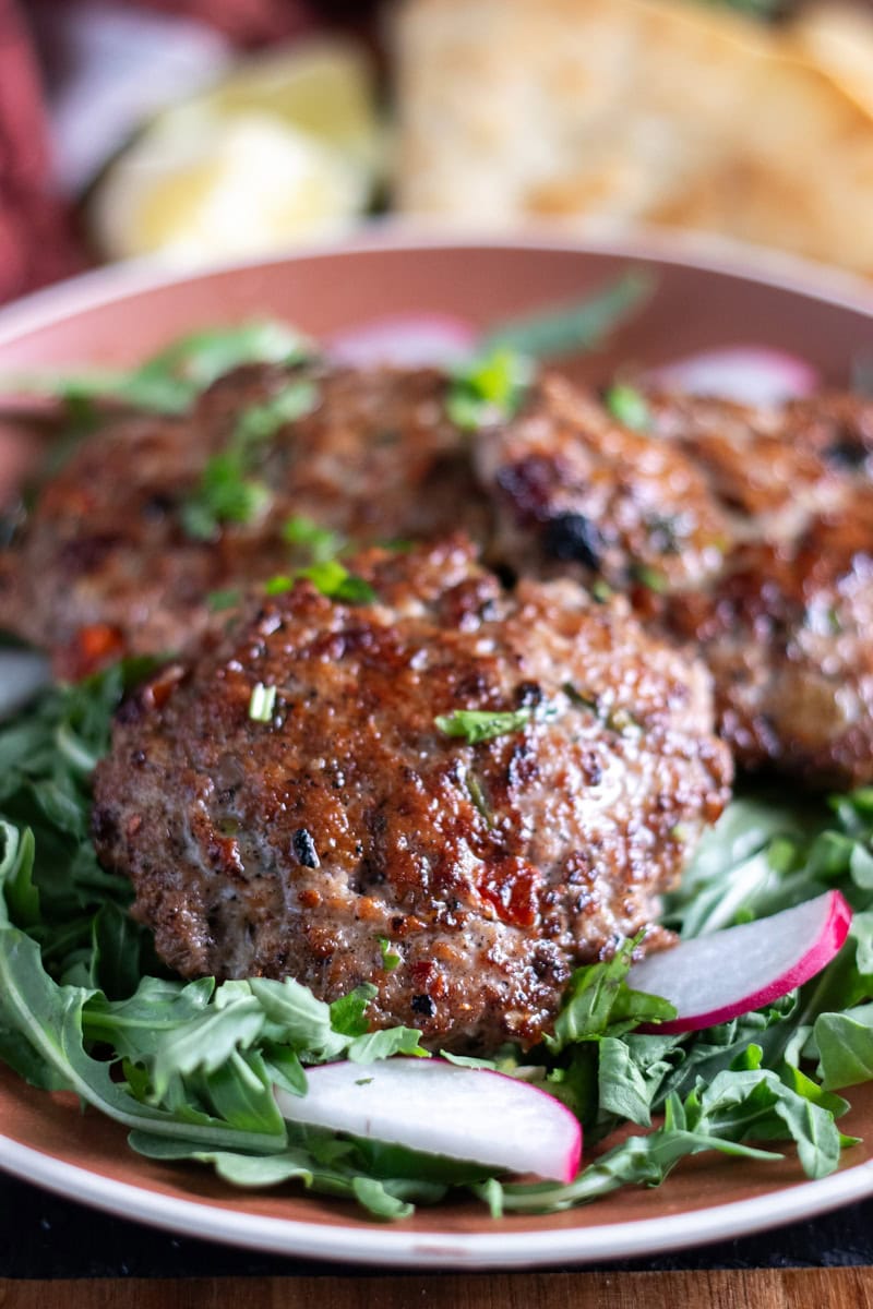 chicken chapli kababs on a bed of arugula and radish