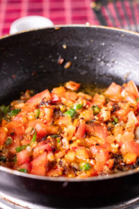 tomatoes and spices added to a pan