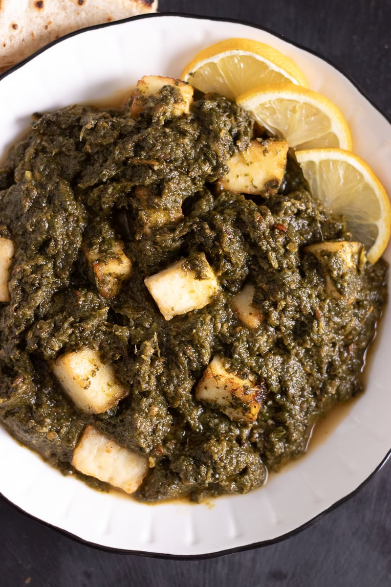 top down view of a plate of palak paneer garnished with lemon