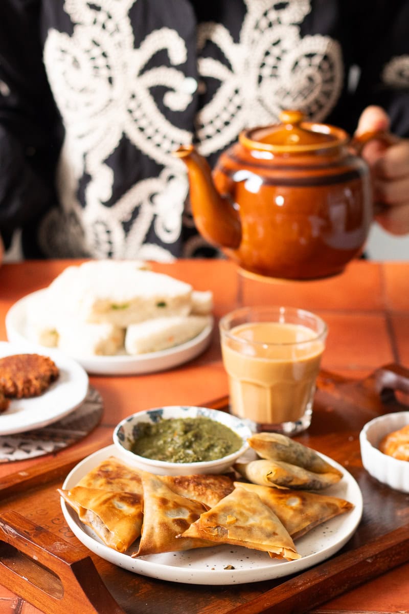 table set for tea with keema samosas, sandwiches and shami kabab