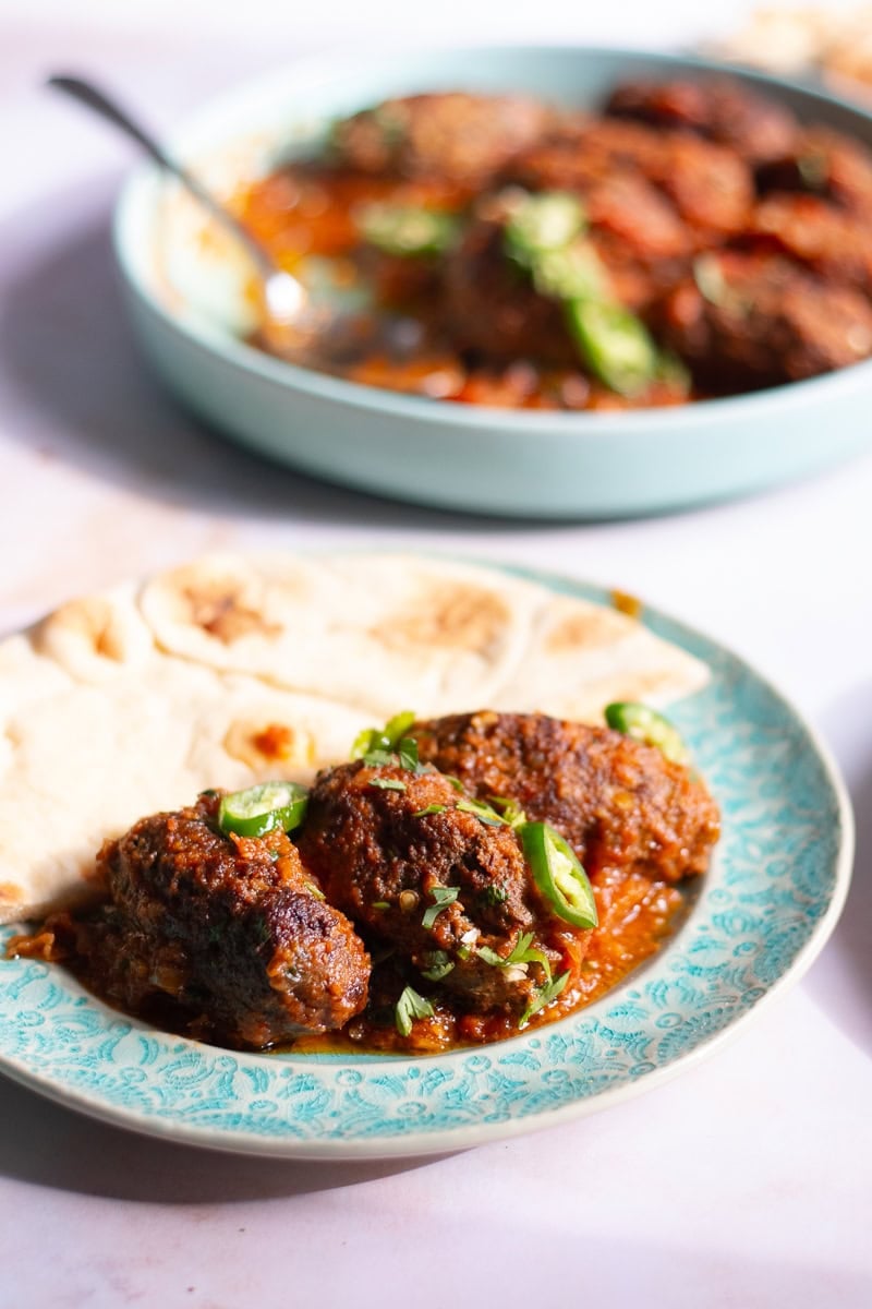 handi kabab masala and naan on a blue plate