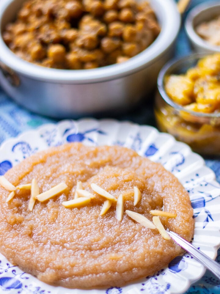 suji ka halwa, soft one pot version on a plate with a dish of chana and aloo poori in the background