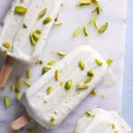 pista kulfi on a marble board with pistachios scattered over top